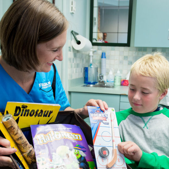 dental hygenist giving young patient toy