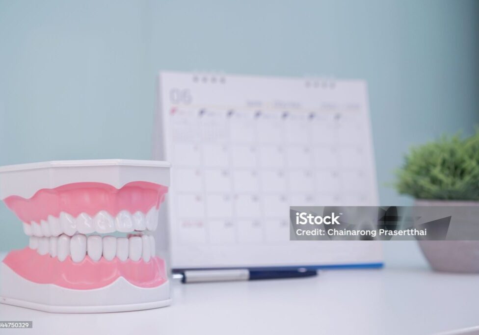 close up on teeth model denture with standing calendar for make appointment at dentist's office table , healthcare concept