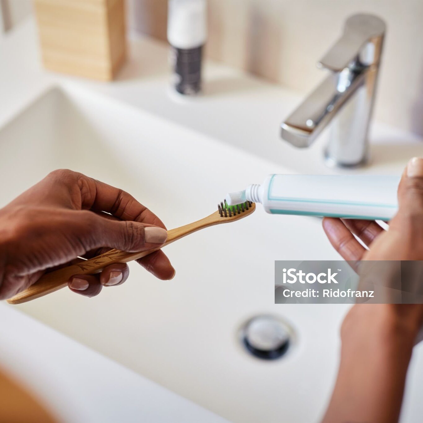 Black woman hand squeezing whitening paste on wooden toothbrush, taking care about mouth hygiene. Close up of female hands applying toothpaste on ecological bamboo tooth brush, plastic free concept. Oral hygiene and environmental responsibility concept.